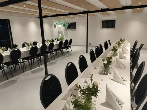 Festlokale dækket op med lange borde og polstrede stole